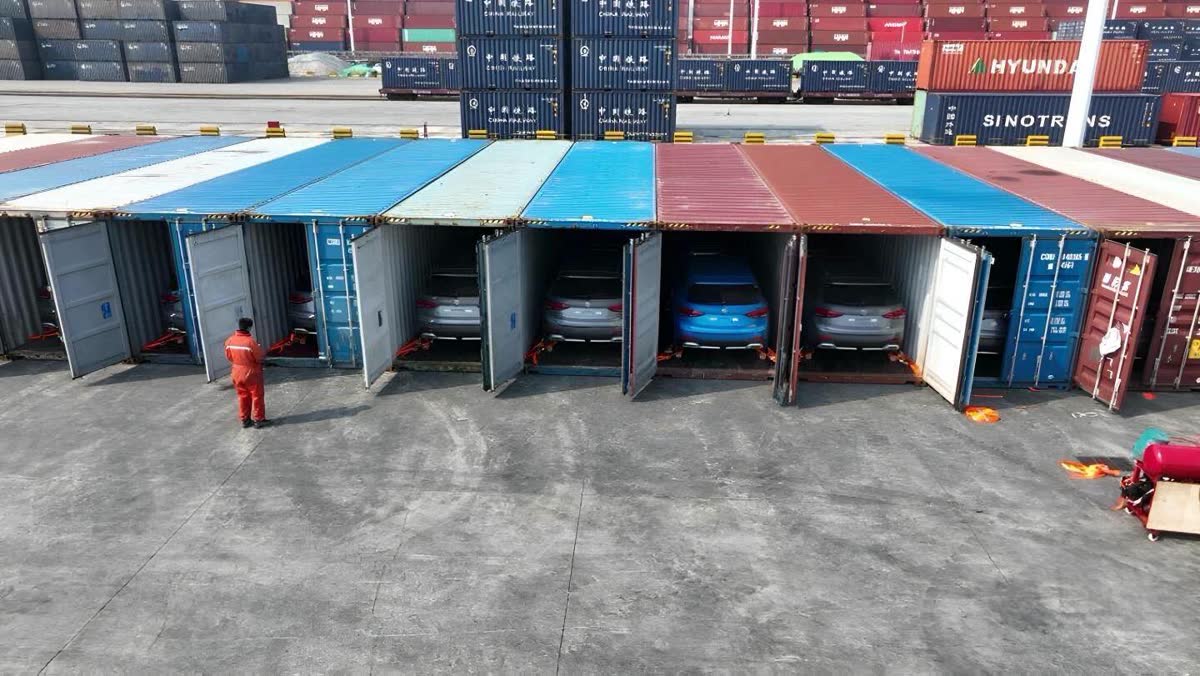 A row of 40ft containers with the doors open and vehicles loaded inside