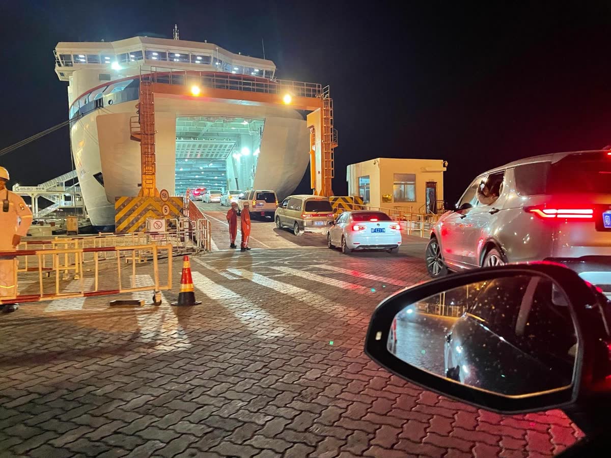 Vehicles queuing at the stern ramp of a roll-on roll-off vessel at night